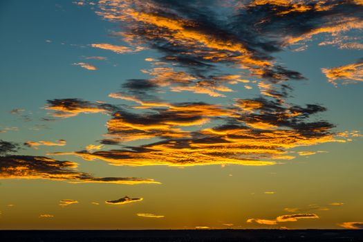 The sun sets over Albuquerque, New Mexico lighting clouds in the sky from underneath.