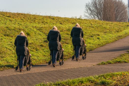 Three women with a baby carriage while walking with the grandson.