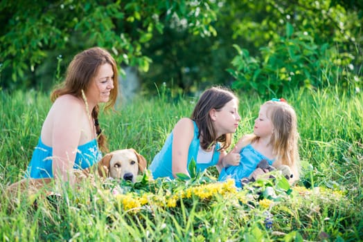 mother, two daughters and a dog sitting on the grass in the garden