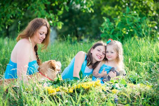 mother, two daughters and a dog sitting on the grass in the garden
