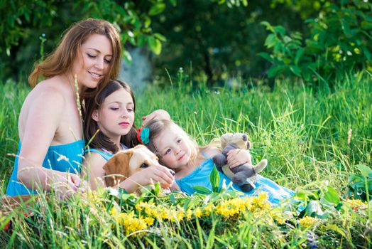 mother, two daughters and a dog sitting on the grass in the garden