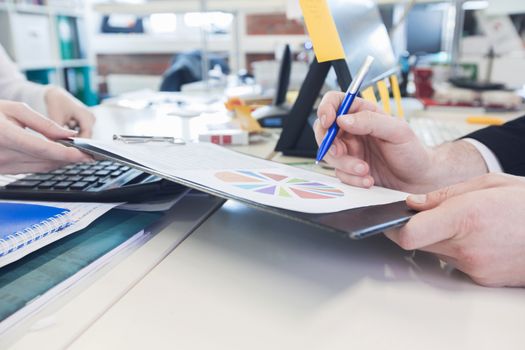 Business people with pens pointing at diagram on business document at meeting