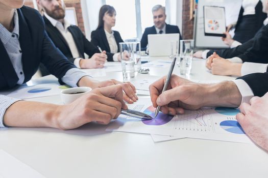 Business people with pens pointing at diagram on business document at meeting