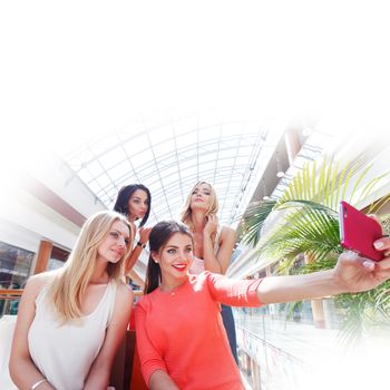 Happy female friends taking selfie in shopping mall