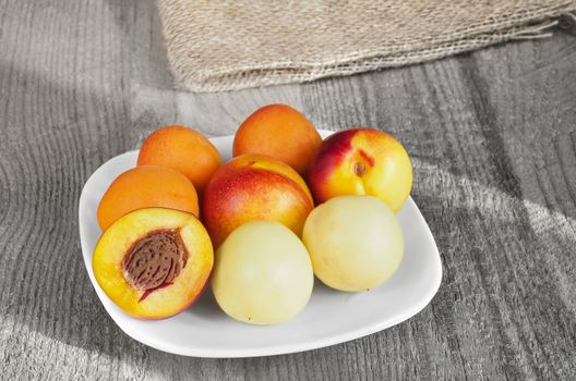 Southern fruit, apricots and nectarines in a plate on a gray wooden background