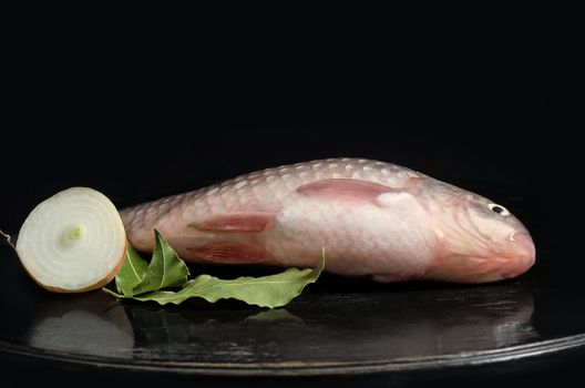 Raw freshwater fish on the table and a black background.Place for text.