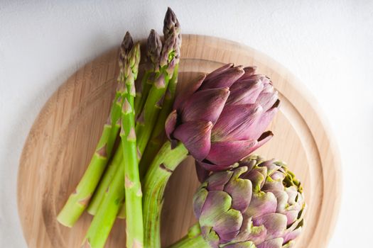 Artichokes and asparagus on a wooden board