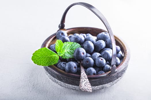 Fresh Blueberries and mint served on a white surface