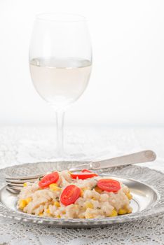 Plate of creamy risotto with a glass of white wine in the background.