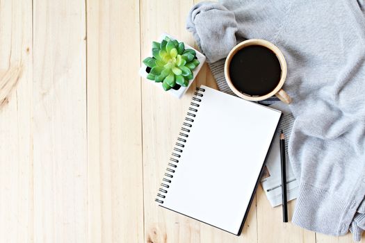 Business, Holiday or weekend concept : Flat lay of knitted sweater, cup of coffee and blank notebook paper on wooden background