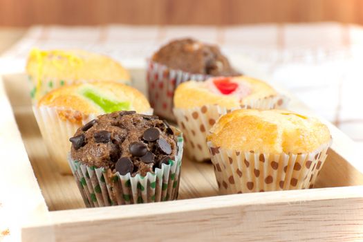 Cupcake various flavors in wood tray on wood table.