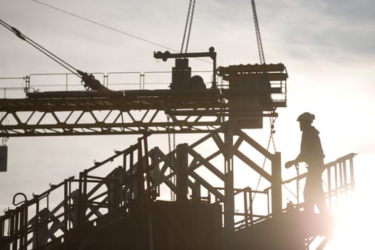 Construction worker, crane and building at sunset, France