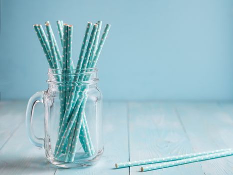 Mason jars with blue paper straws on blue wooden background. Ideal for summer drinks and smoothies. Copy space