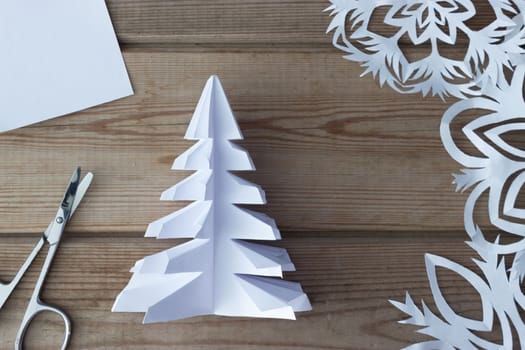handmade paper snowflakes and scissors on wooden table, background