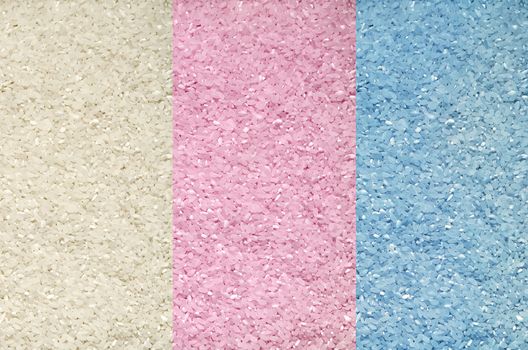 Textured background of grains of rice scattered on the surface, blue, white and pink
