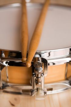 Drum sticks over a snare drum with wood background