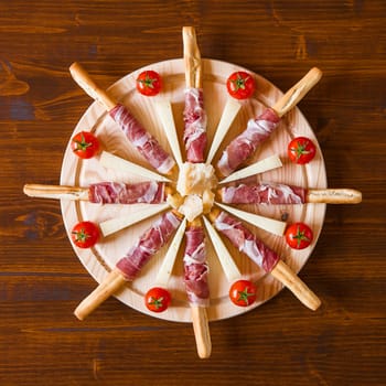 Chopping board with ham cheese and cherry tomatoes seen from above