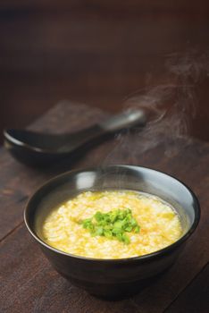 Asian congee bowl on rustic wooden table background.