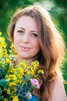 portrait of a woman with wildflowers in the summer sunny day