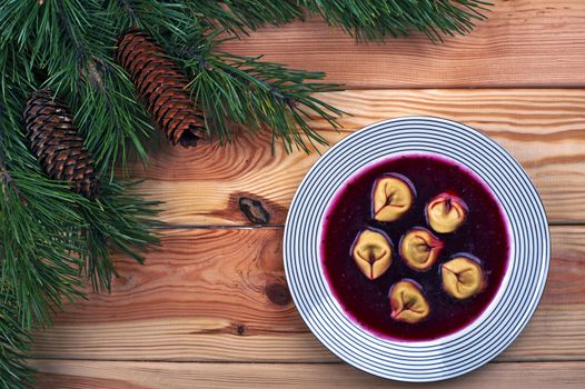 Polish red borscht with dumplings on a wooden table