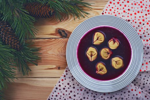 Polish red borscht with dumplings on a wooden table