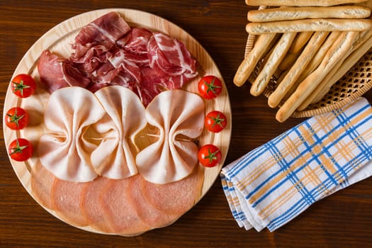 Salami cutting board breadsticks and napkin seen from above