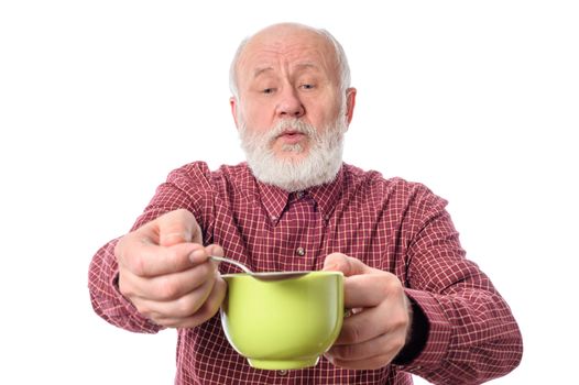 Cheerful and smiling handsome bald and bearded senior man with big green cup and teaspoon, isolated on white background