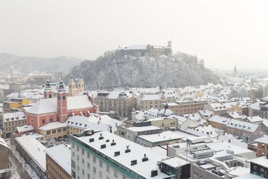 Aerial panoramic view of Ljubljana in winter time. Slovenia, Europe. Rooftops covered in snow.