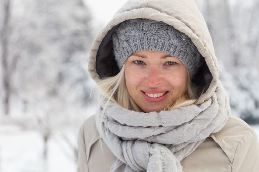 Portrait of cute casual young woman outdoor in snow in cold winter time.