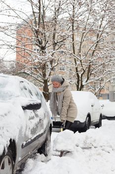 Independent woman shoveling her parking lot after a winter snowstorm.