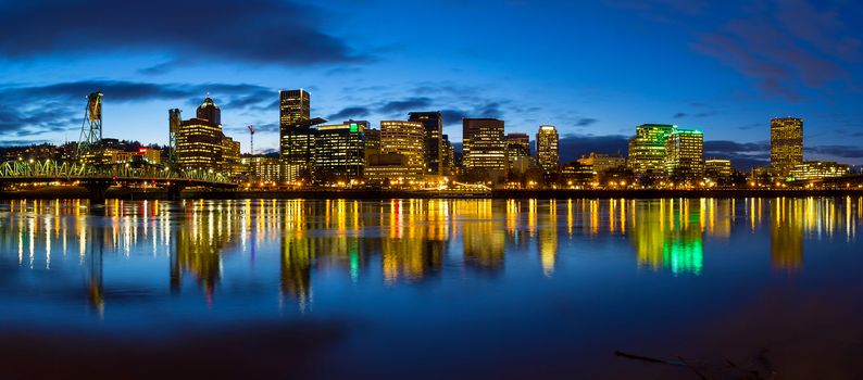 Portland Oregon downtown city skylinw by Hawthorne Bridge along Willamette River at evening blue hour panorama