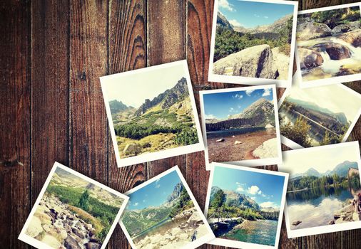 Heap of the vintage photos from holiday in mountains with traditional white frame placed on wooden desk.