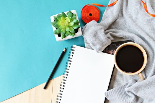 Business, Holiday or weekend concept : Flat lay of knitted sweater, cup of coffee and blank notebook paper on wooden background