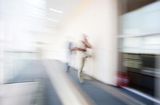 A motion blurred background image of an interior of hospital, airport or other with some human figures.