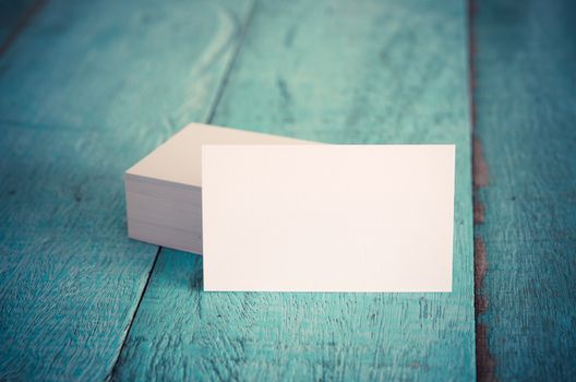 Blank business cards on blue wooden table. Vintage filter.