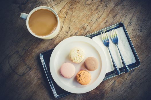 Cup of coffee with macarons set on wooden table. Top view with copy space, flat lay. Vintage filter.