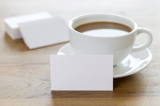 Blank business cards and cup of coffee on wooden table. Corporate stationary branding mock up.