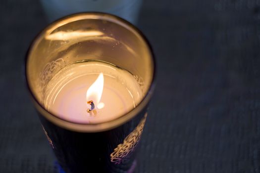 burning candle in a glass with a dark blue background