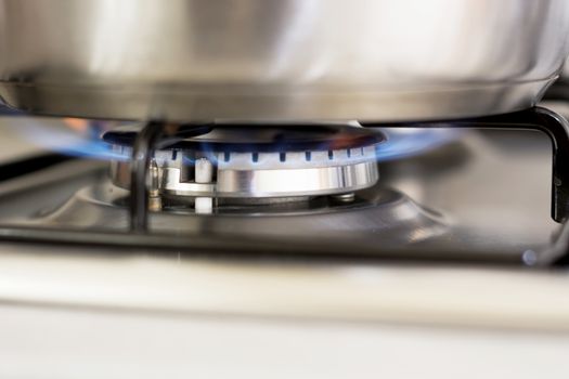 saucepan on burning gas in hearth ring of kitchen stove