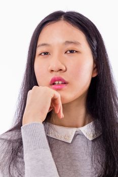 Portrait of Chinese teenage girl looking at camera with chin on hand, serious expression
