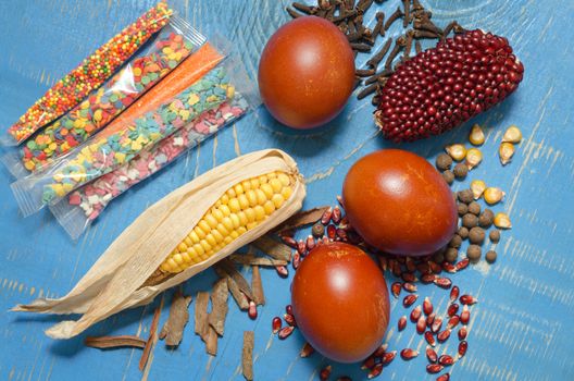 Easter eggs, corn, spices and decorations on a blue wooden background.