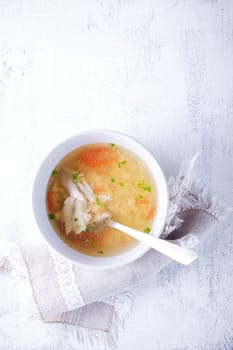 Homemade chicken soup with a spoon on a white napkin