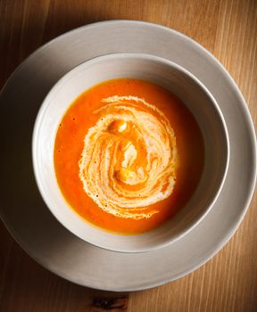 Pumpkin soup with cream served on a table.