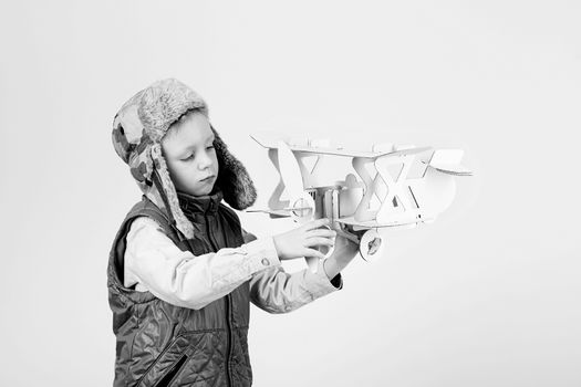 Child boy playing with paper toy airplane and dreaming of becoming a pilot against a white background. Black and white photography