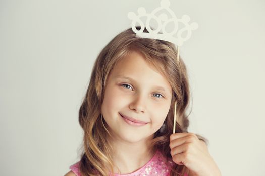 Portrait of a lovely little girl with white paper crown against a white background