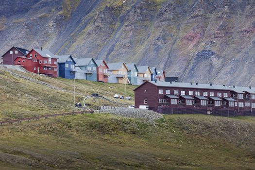 Idyllic scenic view, colorful houses and green field with arctic flowers against the background of dramatic sky and barren mountain in Longyearbyen, Spitsbergen archipelago (Svalbard), Norway, Europe




