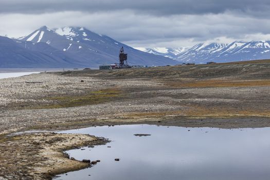 Beautiful scenic view of blue gulf under barren mountain range with melting snow against the background of dramatic evening sky near Barentsburg, Spitsbergen (Svalbard island), Norway, Greenland sea

