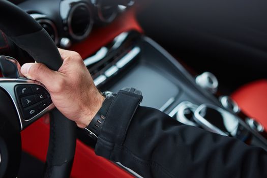 The male driver hands holding steering wheel