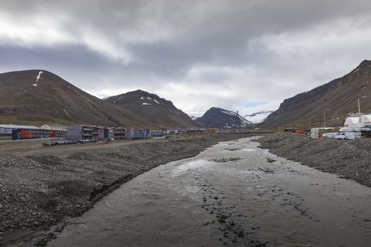 Beautiful scenic view of blue gulf under barren mountain range with melting snow against the background of dramatic evening sky near Barentsburg, Spitsbergen (Svalbard island), Norway, Greenland sea

