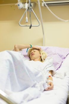 Bedridden female patient lying in hospital bed, recovering after surgery.